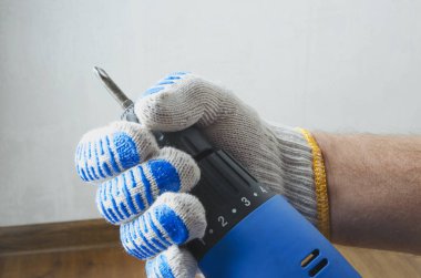 Beyaz duvar ve zemin karşı mavi tornavida ile erkek el closeup