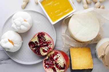 Tablo gouda, peynir, ricotta, buratta, fıstık, nar, tatlım lezzetli yemek için hazır. Hizmet tablo, ürünler bol üstten görünüm