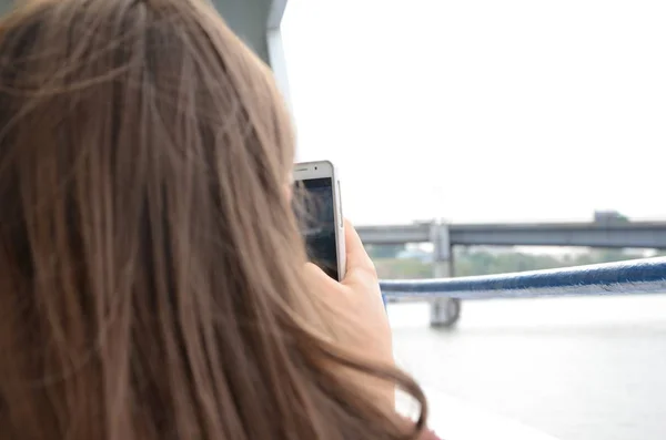 Girl using her cell phone to take picture of bridge during walk