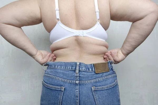 Back view of woman`s muffin top,rolls on her back.Woman showing her fat shape.Concept of unhealthy lifestyle