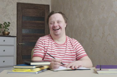 Happy smiling down syndrome boy likes to draw and writing,home interior