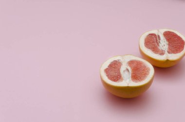 Olgun ve taze greyfurt, pembe arka plan dilimlenmiş. Tatlı renkler