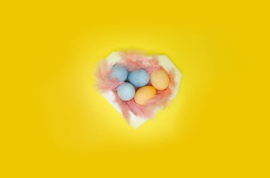 Yumurta boyalı, egzotik tüyler kalp kutu, üstten görünüm kurdu. Paskalya kutlamaları kavramı