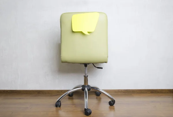 Back of office chair and paper speech bubble on it.What are employees thinking about during the work?