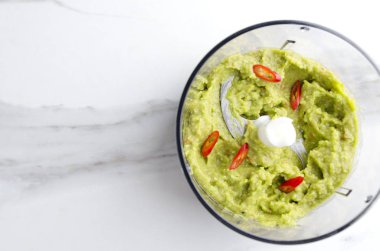 Üstten Görünüm blender ve biber biber ile karışık guacamole. Hazırlık avokado tabanlı dalarak mutfak kavramı