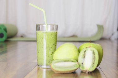 Tatlı taze yapılmış yeşil smoothie ve meyveler, ahşap zemin, arka plan üzerinde Spor donatımı