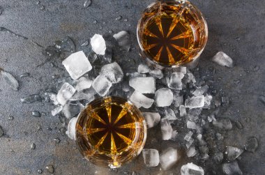 Gri yüzeyi üstten görünüm gözlük brendi ve buz parçaları. Parti içecekler