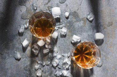 Bardaki kutlama. Alkollü içecekler ve buz küpleri, üstten görünüm ile gözlük çifti. Gri masasında alışılmadık şekilde gözlük viski ile hizmet