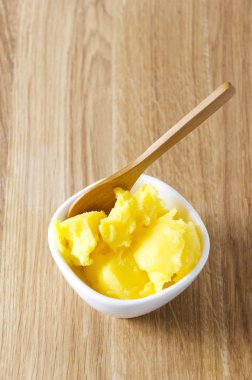 Soğuk ghee ahşap masa üzerinde beyaz kase. Lezzetli ve sağlıklı türü tereyağı