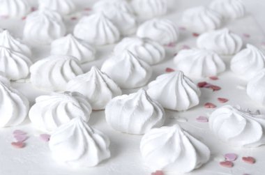 Küçük meringues beyaz yüzey üzerinde. Tatlı snack ve kalp şeklinde dekorasyon