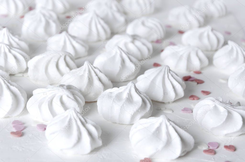 Little meringues on white surface.Sweet snack and decoration in heart shape