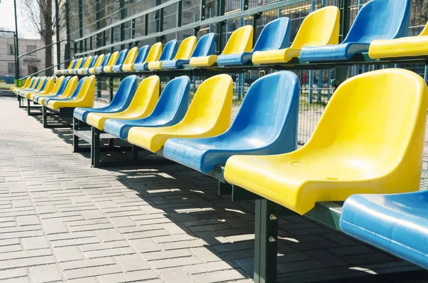 学校のスポーツコートの青と黄色の座席の空の行 — ストック写真