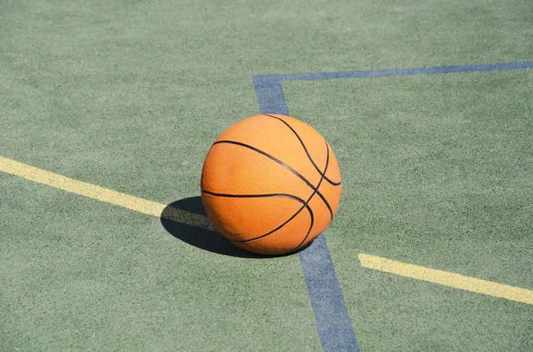 Basketball ball on the rubber sport ground outdoor. Closeup of orange ball on the school playground