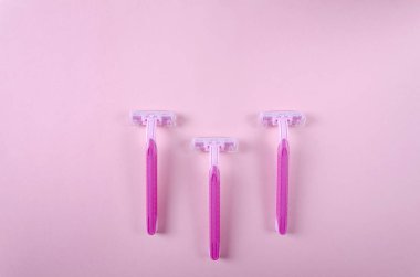 Pembe arka planda kadın için üç jilet, üstten bak. Depilasyon kavramı
