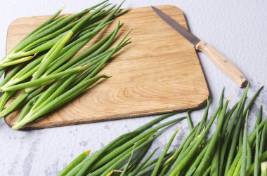 Mutfak masasında taze taze soğan. Prepering ve pişirme gıda. Bahar soğan, kesme tahtası ve bıçak kithcen masada