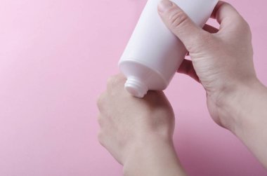 Kozmetik krem ile kadın elleri ve plastik tüp closeup. Kadın ellerine nemlendirici krem sıkma
