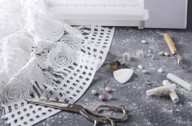 Gri masa üzerinde kumaş, iplik, düğme, makas ve dikiş ekipmanlarının kapatılması