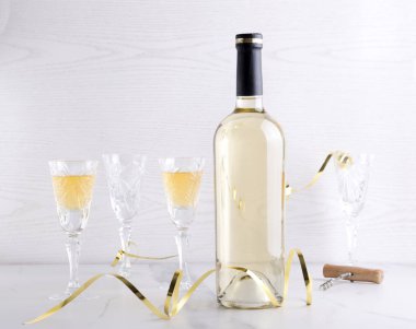 Parti zamanı. Beyaz şarap ve şarap bardakları şişe, hafif arka plan karşı beyaz masada tatil dekor