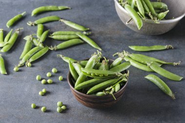 Taze bakla bezelye aldı. Gri masada bezelye ile Bowl. Tatlı bezelye taze bahar hasat