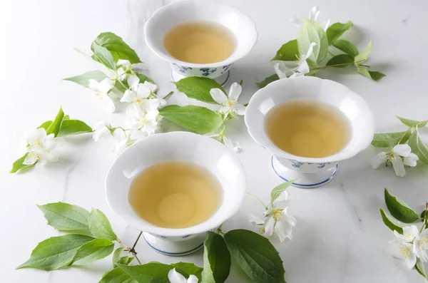 茶时间 白桌上的热绿茶和茉莉花枝 — 图库照片