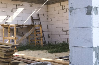 Ev inşaatı işi. Tuğla duvarın yakınında ahşap merdiven ve iskele 