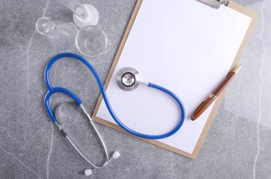 Doktorun işyeri üst görünümü. Gri masada temiz kağıt, tıbbi ekipmanlar