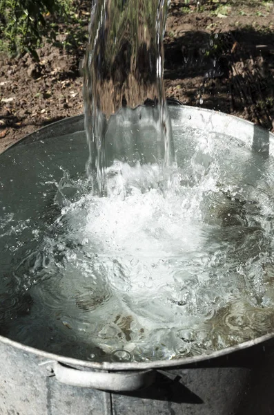 在花园里将水倒入金属浇水罐中 — 图库照片