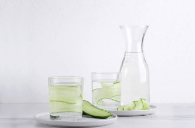 İki bardak ve tabak sağlıklı salatalık su şişe. Mutfak beyaz masa