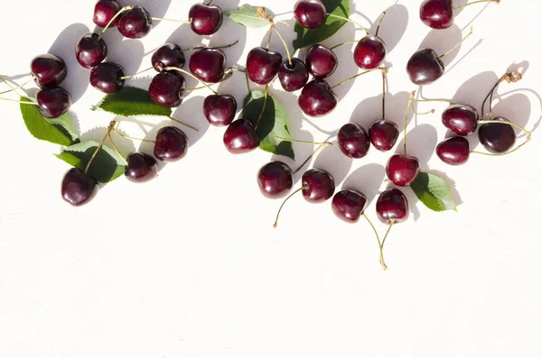 Top view of fresh just picked cherries with green leaves on the white background