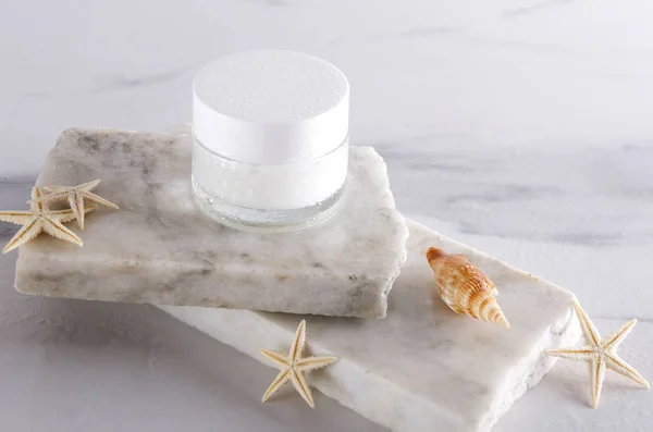 Cosmetic glass jar on the white stones and seashells.Mineral moisturizing cream