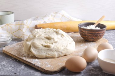 Ahşap tahta üzerinde hazırlanan pizza hamuru. Büyük ev yapımı hamur praparation için Malzemeler. Süt, yumurta, un, gri mutfak masasında oklava fincan