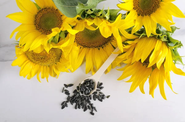 Top view of bouquet of sunflowers and seeds on the white surface