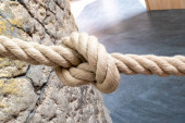 Természetes szálból készült kötél, amelyet védőkötélként használnak, egy természetes kőfalhoz kötve, középen csomóval..