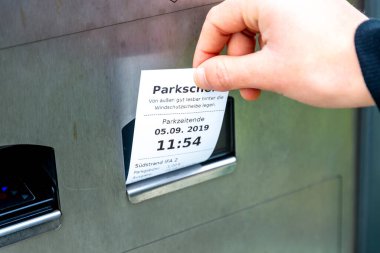 Fehmarn, Schleswig-Holstein / Almanya - 05.09.2019: Bir el park cezası makbuzundan bir park cezası çekiyor, park süresi sona erdiğinde ve nereye park edebileceğiniz kaydediliyor. Makine metalden yapılmıştır..