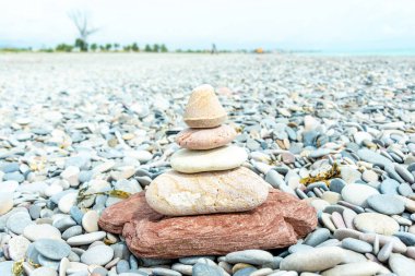 Dikkatle dengelenmiş pürüzsüz taş yığını çakıllı bir plaj zeminine karşı bir Zen hissi yaratıyor.