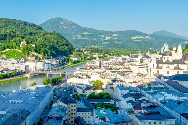 Salzburg, Salzburg - Avusturya - 06-17-2021: Salzburg silueti Salzach Nehri ile, tarihi mimari ve Alp ufkunun altındaki bereketli Kapuzinerberg tepesi