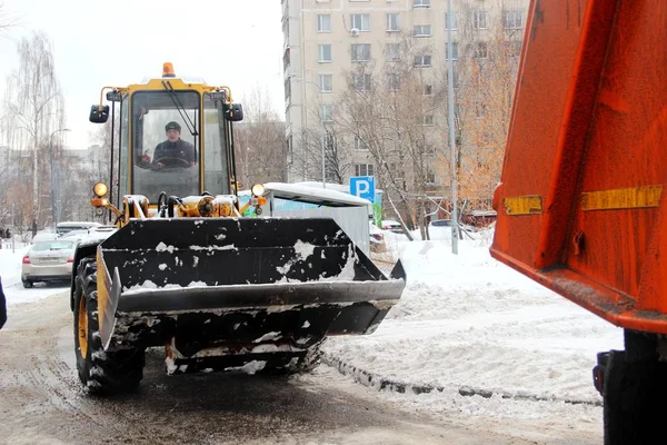 Городские службы уборки снега специальное оборудование после снегопада. городских коммунальных услуг. Трактор загружает снег в грузовик . — стоковое фото