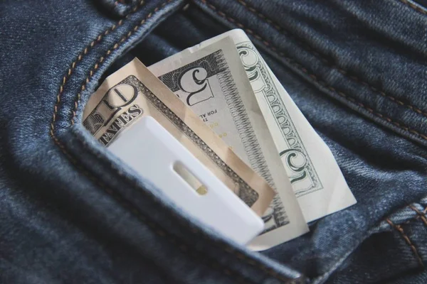 No much Money and card key in a pocket of blue jeans close-up. the concept of office workers. blur — Stock Photo, Image