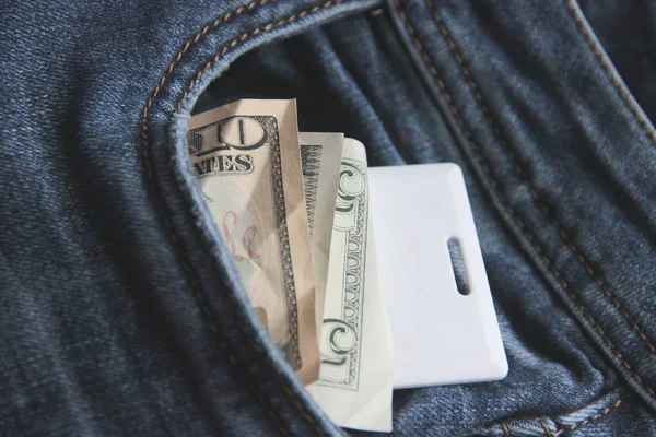 Dollar and card key in a pocket of blue jeans close-up. — Stock Photo, Image