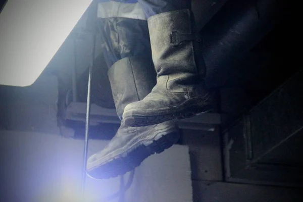 Tarpaulin boots in the light of a lantern during the works. Work of industrial clean of sewage, plumbing in the building.