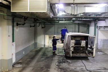 Endüstriyel temiz kanalizasyon, sıhhi tesisat, havalandırma arabada binanın temelinde çalışır. İki adam, özel araç, bir merdiven merdiven.