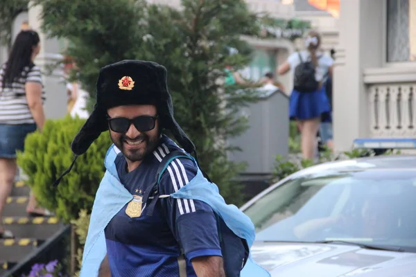 Happy tourister football fan in national Russian military winter hat with cockade hat-ushanka — Stock Photo, Image