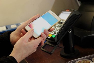 kadın bir kahve dükkanında PayPal ödeme sistemi ile ödeme satın almak için ödemek için bir telefon tutuyor