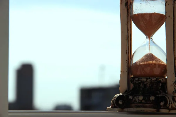 Reloj de arena antiguo en el fondo de los edificios urbanos modernos y el cielo azul en un día soleado —  Fotos de Stock