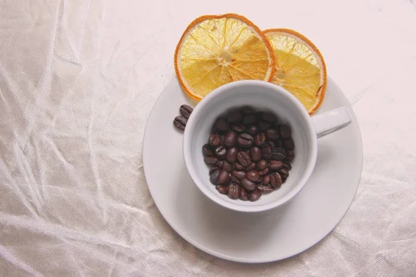 Cangkir dan piring, biji kopi, irisan jeruk kering di atas meja berkilauan . — Stok Foto