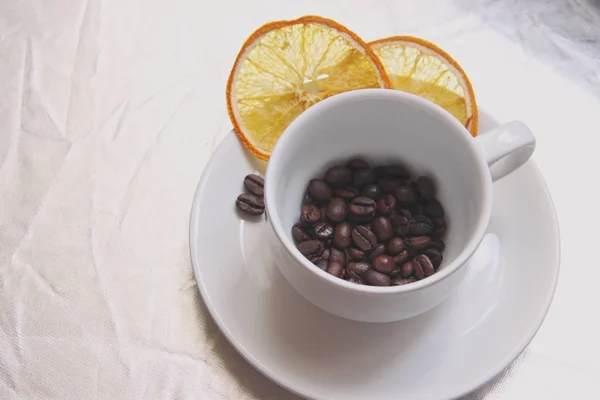 Pair Cup and saucer, coffee beans, slices of dried orange on silver table.