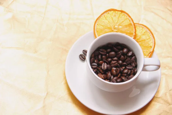 Cup and saucer, coffee beans, slices of dried orange.