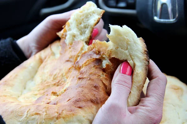 Women hands with a red manicure tear off a piece of oriental flatbread.  Tandoor pita Asian cuisine. — 스톡 사진