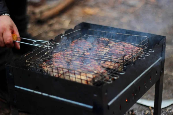 Человек жарит много сочных кусочков мяса на гриле. делает шашлык из свежего мяса — стоковое фото