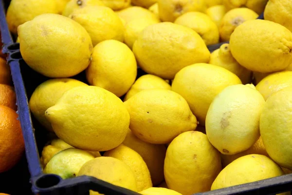 Muchos limones amarillos en la caja, fondo. Buena cosecha de cítricos — Foto de Stock